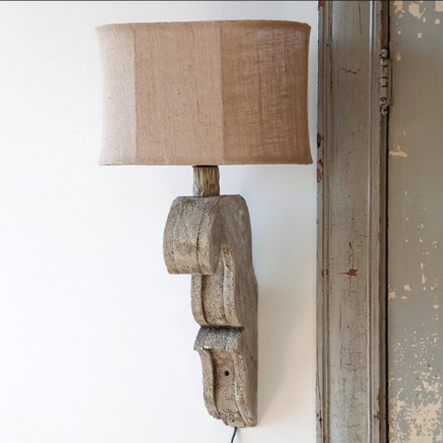 La lampe-applique à volutes en bois avec abat-jour en toile de jute