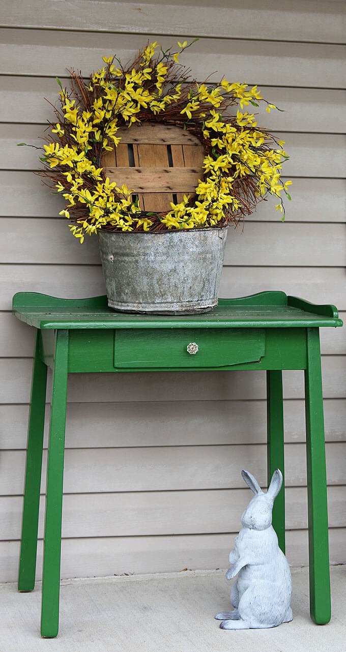 Mesa antigua verde, estatua de conejito, corona floral