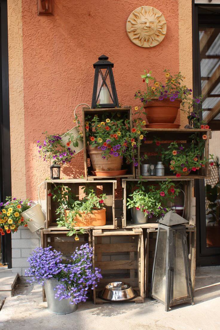 Estantes de cajas de madera con flores en macetas