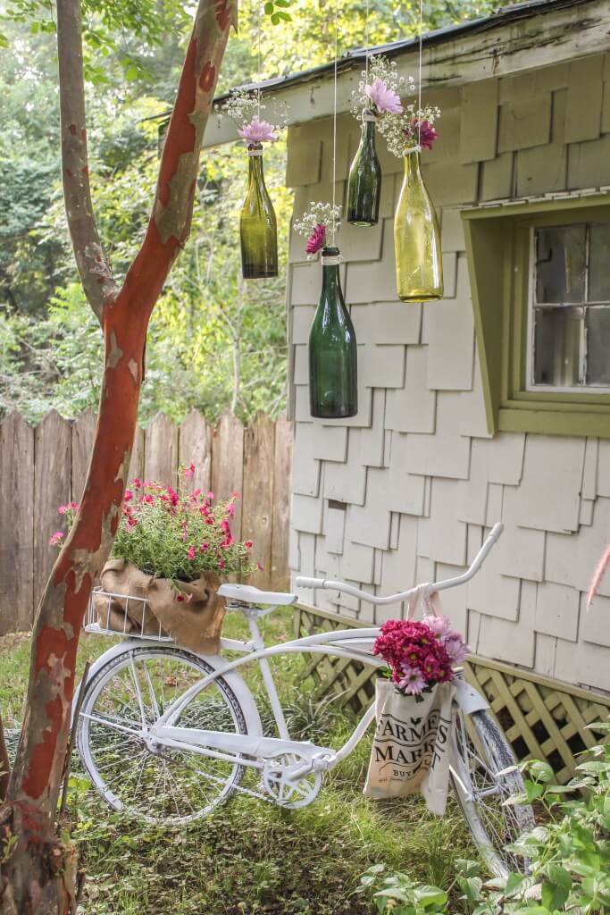 Rower w stylu vintage i zielone szklane butelki wypełnione kwiatami