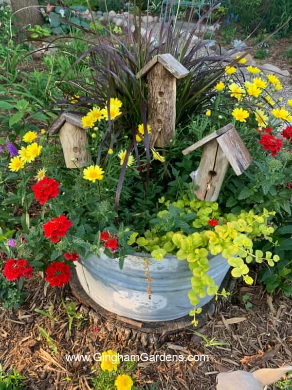 Vanový květináč praskající s rostlinami a umělými ptačími budkami